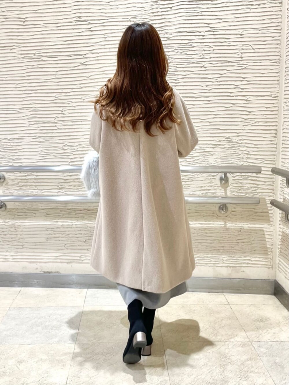 ブラック系のブーツ、グレー系のスカート、ベージュ系のステンカラーコートを着用したレディースの冬コーディネートの3枚目の写真