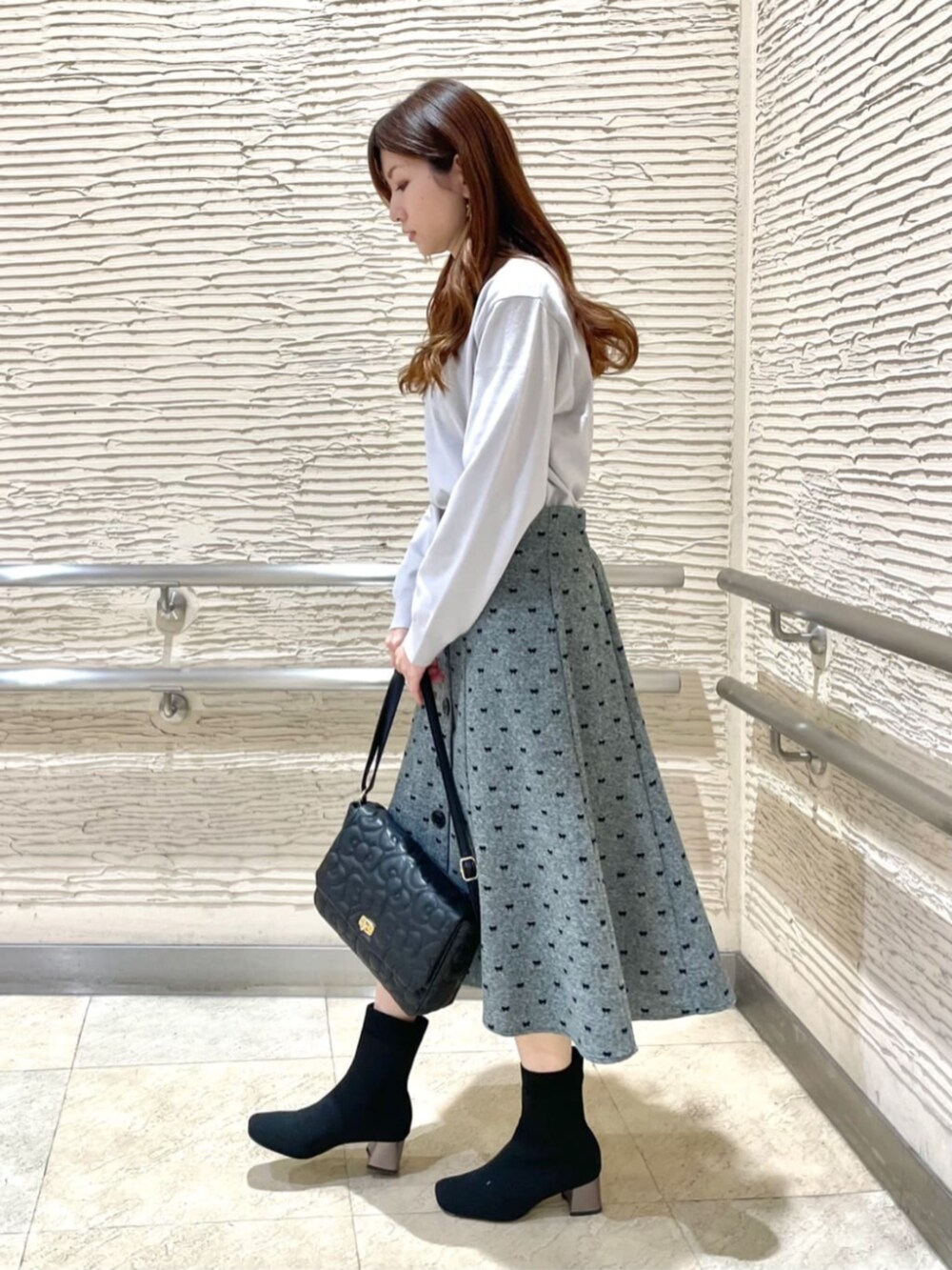 ブラック系のブーツ、ブラック系のショルダーバッグ、グレー系のニット/セーターを着用したレディースの冬コーディネートの2枚目の写真