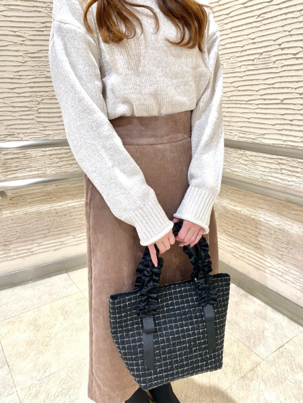 ブラック系のブーツ、ホワイト系のニット/セーター、ブラウン系のスカートを着用したレディースの冬コーディネートの4枚目の写真