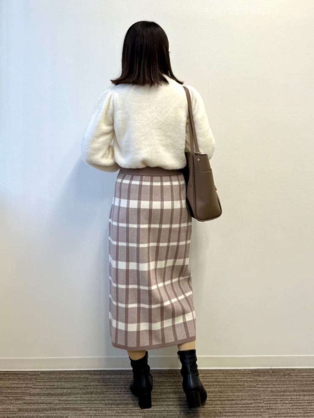 ベージュ系のセットアップ、ホワイト系のニット/セーター、ブラウン系のトートバッグを着用したレディースの冬コーディネートの3枚目の写真