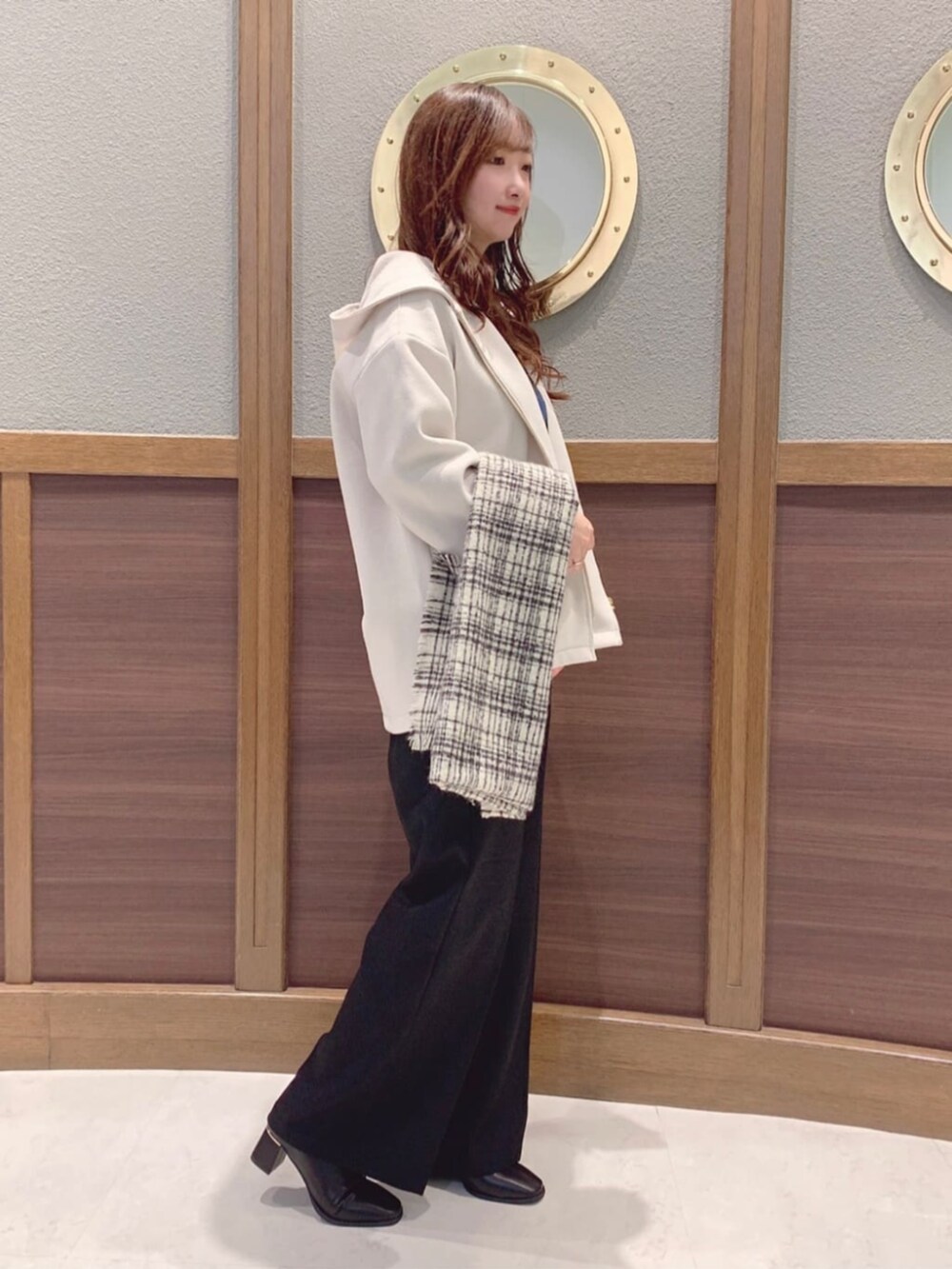 ブラック系のブーツ、ホワイト系のその他アウター、ブルー系のニット/セーターを着用したレディースの冬コーディネートの2枚目の写真