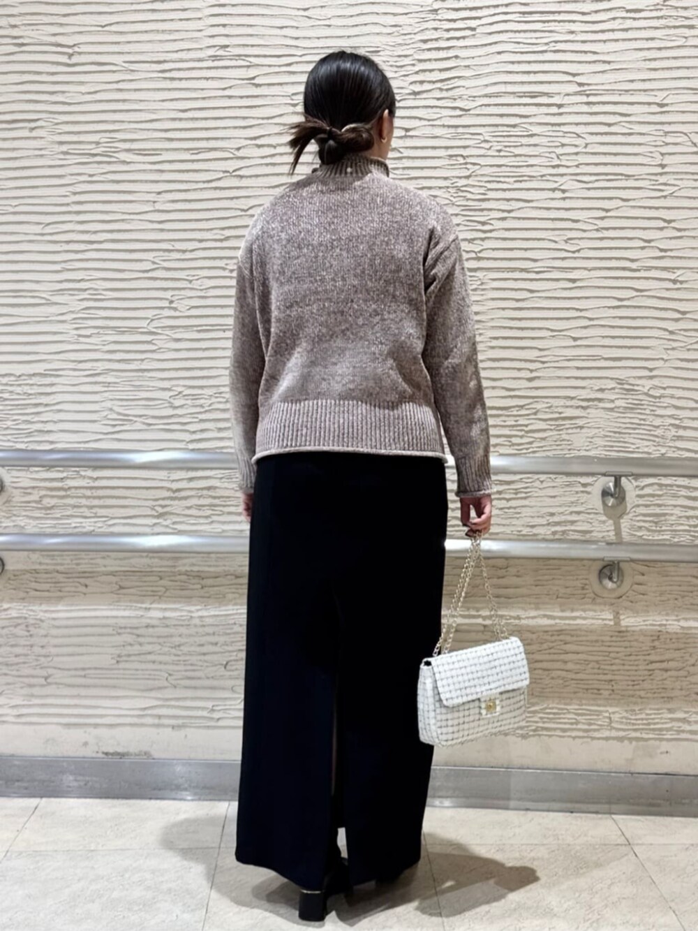 ブラック系のブーツ、ホワイト系のショルダーバッグ、ブラウン系のニット/セーターを着用したレディースの冬コーディネートの3枚目の写真