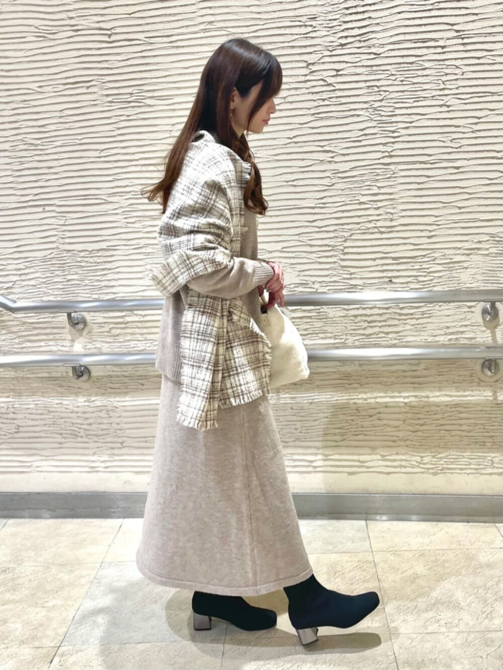 ブラック系のブーツ、ベージュ系のセットアップ、ベージュ系のストール/ショールを着用したレディースの冬コーディネートの4枚目の写真