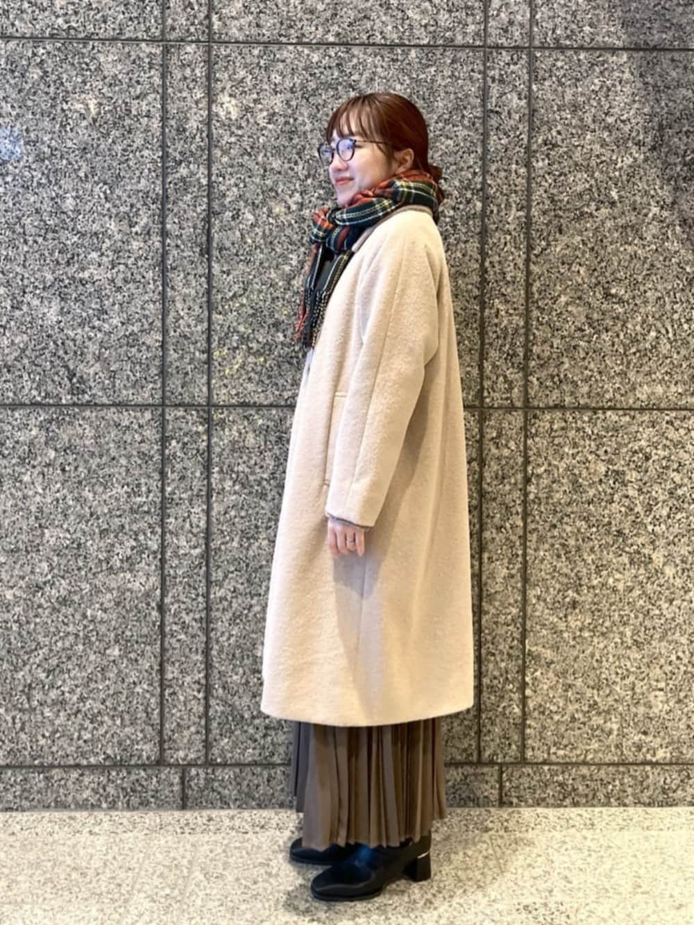 ブラック系のブーツ、ブラウン系のスカート、ベージュ系のステンカラーコートを着用したレディースの冬コーディネートの2枚目の写真