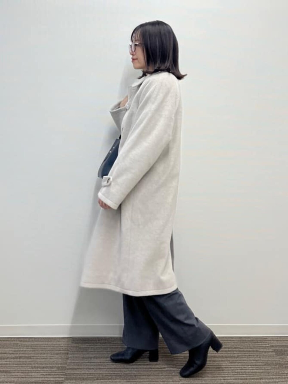 ベージュ系のステンカラーコートを着用したレディースの冬コーディネートの3枚目の写真