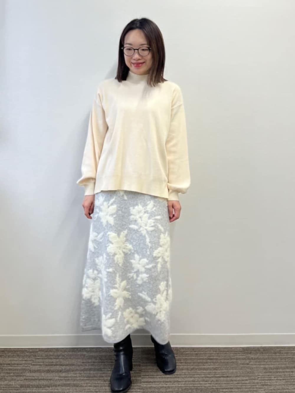 グレー系のスカート、ホワイト系のニット/セーターを着用したレディースの冬コーディネートの2枚目の写真