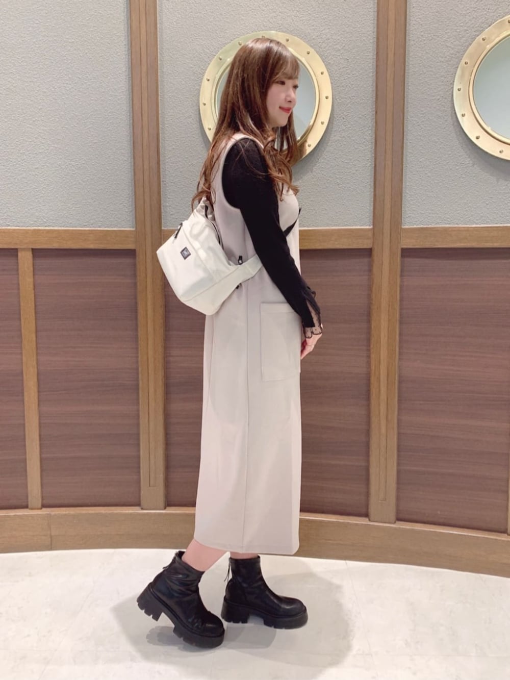 ベージュ系のワンピース、ホワイト系のショルダーバッグ、ブラック系のニット/セーターを着用したレディースの春コーディネートの2枚目の写真