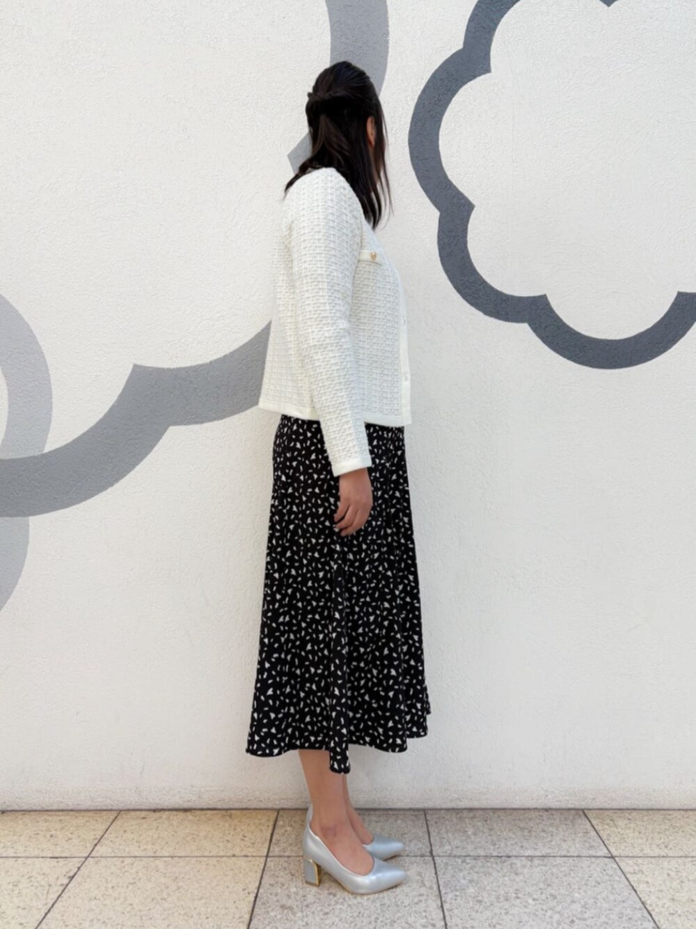 シルバー系のパンプス、シルバー系のハンドバッグ、ブラック系のスカートを着用したレディースの冬コーディネートの2枚目の写真