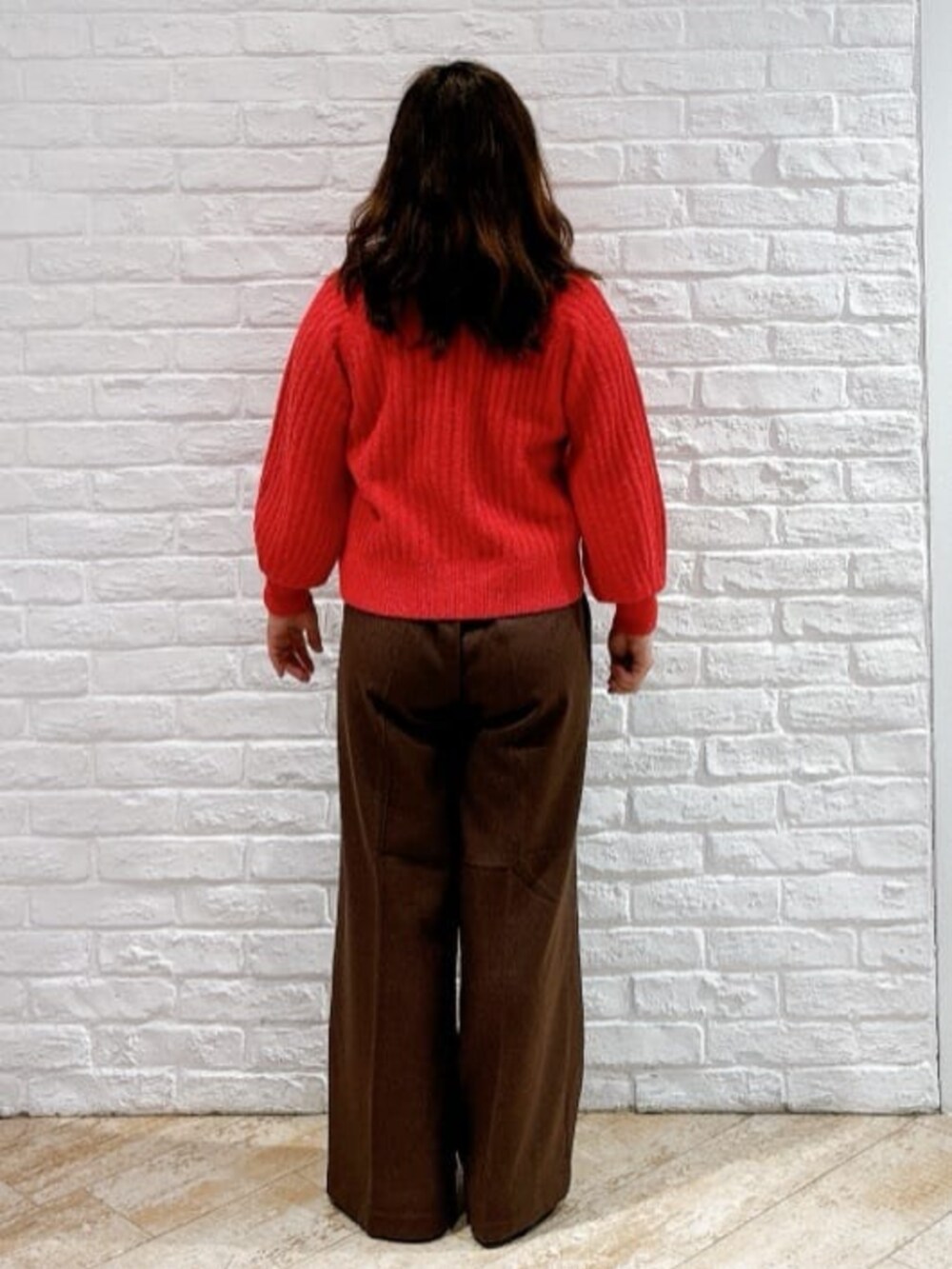 レッド系のニット/セーター、ブラック系のその他アウター、ブラウン系のその他パンツを着用したレディースの冬コーディネートの6枚目の写真