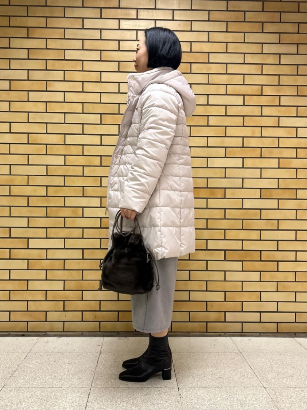 ブラック系のブーツ、ベージュ系のその他アウター、レッド系のニット/セーターを着用したレディースの冬コーディネートの2枚目の写真