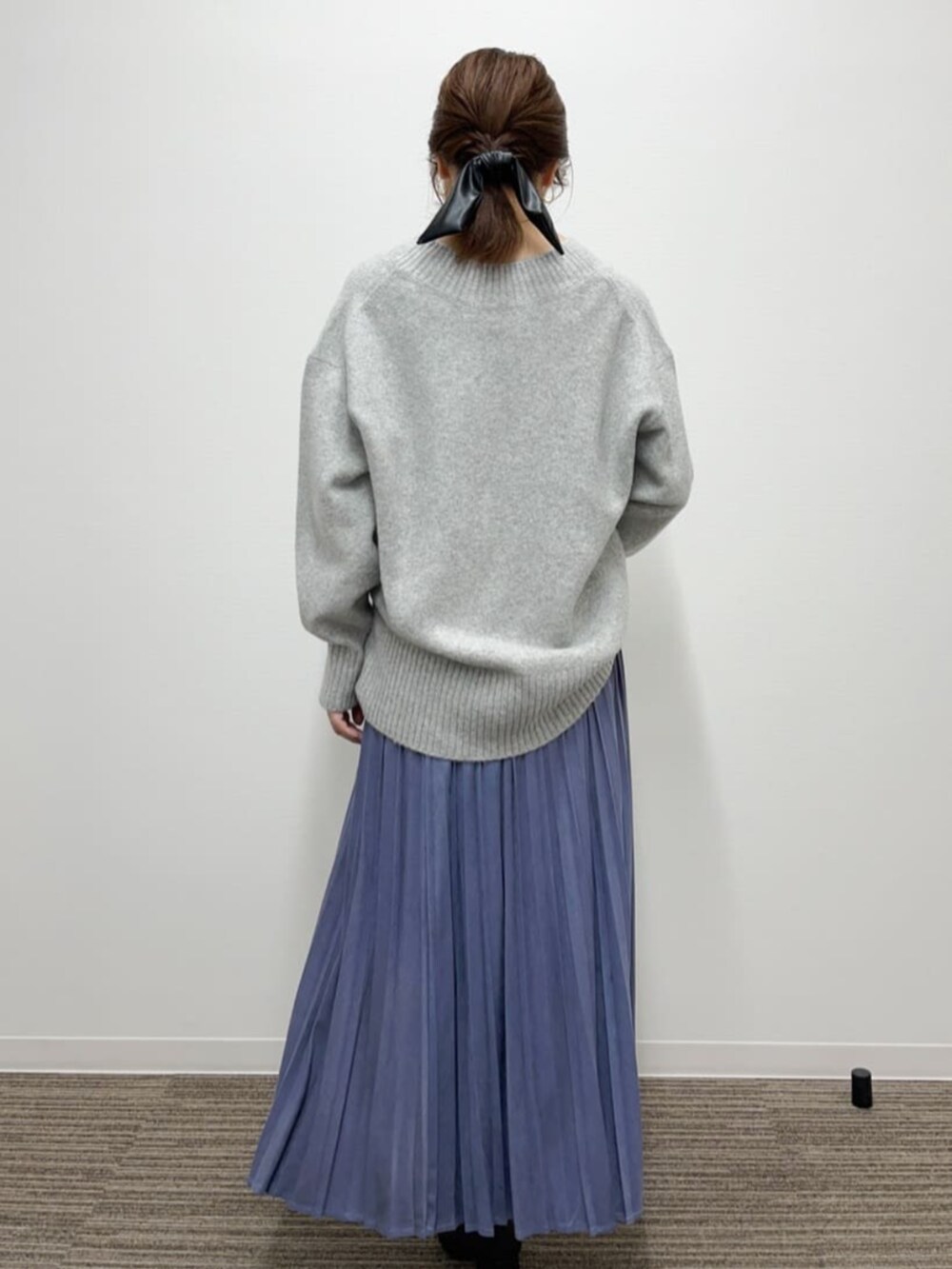 グレー系のニット/セーター、ブルー系のスカート、ブラック系のブーツを着用したレディースの秋コーディネートの3枚目の写真