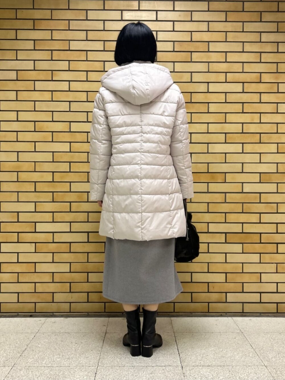 ブラック系のブーツ、ベージュ系のその他アウター、レッド系のニット/セーターを着用したレディースの冬コーディネートの3枚目の写真