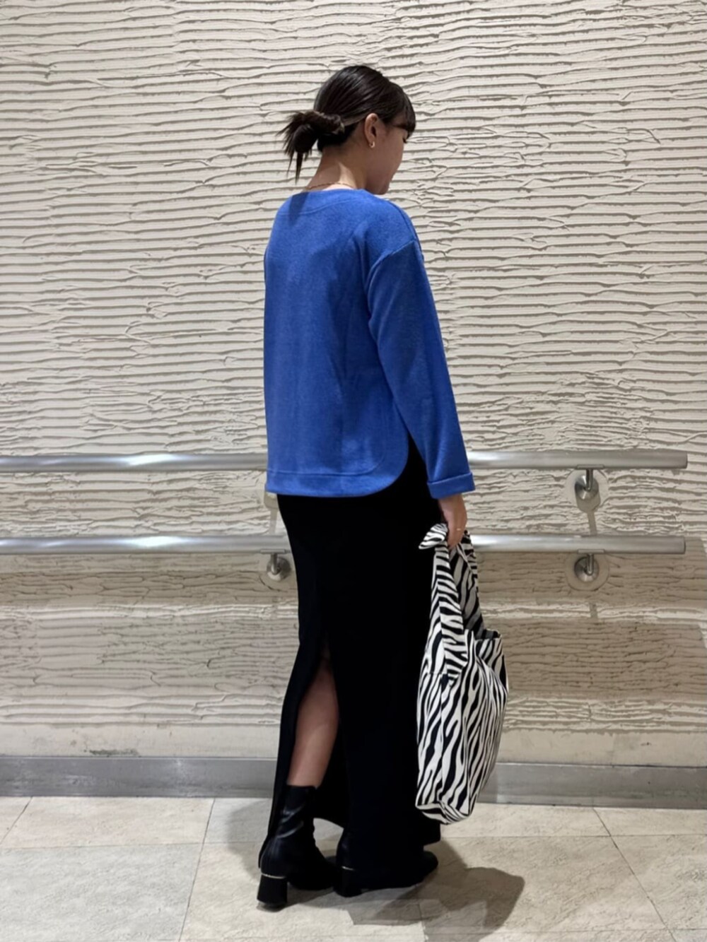 ブラック系のブーツ、ブルー系のTシャツ/カットソー、ブラック系のトートバッグを着用したレディースの冬コーディネートの3枚目の写真