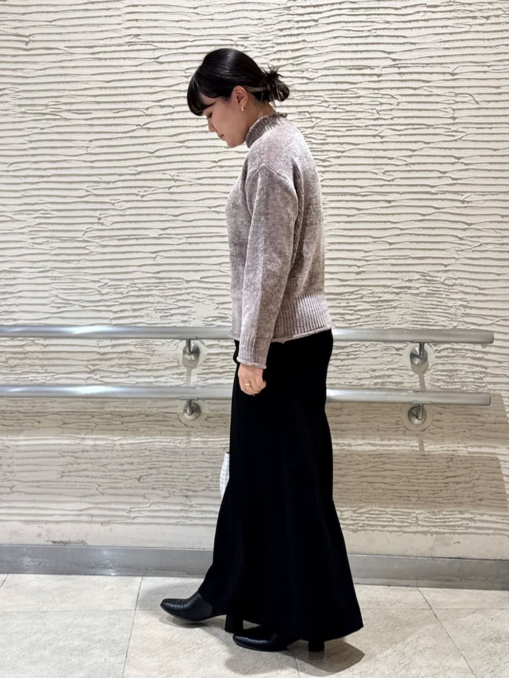 ブラック系のブーツ、ホワイト系のショルダーバッグ、ブラウン系のニット/セーターを着用したレディースの冬コーディネートの2枚目の写真