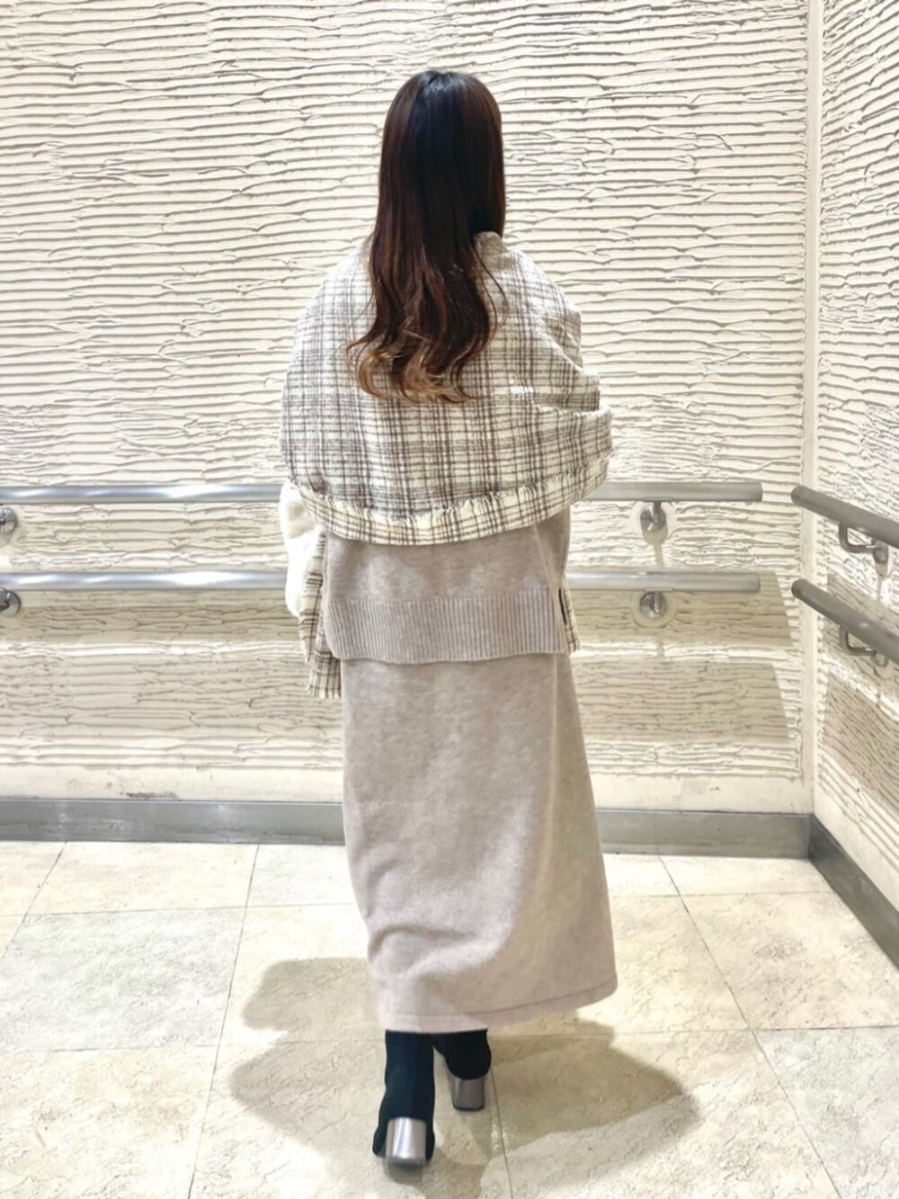 ブラック系のブーツ、ベージュ系のセットアップ、ベージュ系のストール/ショールを着用したレディースの冬コーディネートの3枚目の写真