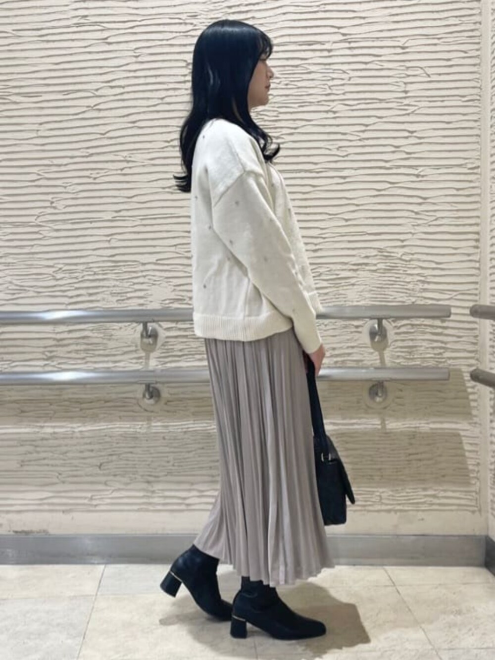 ブラック系のブーツ、ホワイト系のニット/セーター、ベージュ系のスカートを着用したレディースの冬コーディネートの2枚目の写真