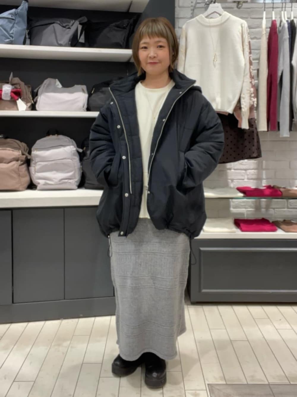 ホワイト系のTシャツ/カットソー、グレー系のスカート、ブラック系のその他アウターを着用したレディースの秋コーディネートの2枚目の写真