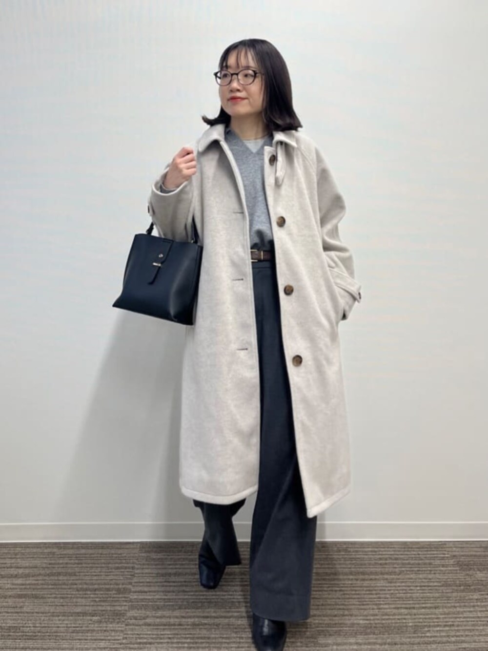 ベージュ系のステンカラーコートを着用したレディースの冬コーディネートの2枚目の写真