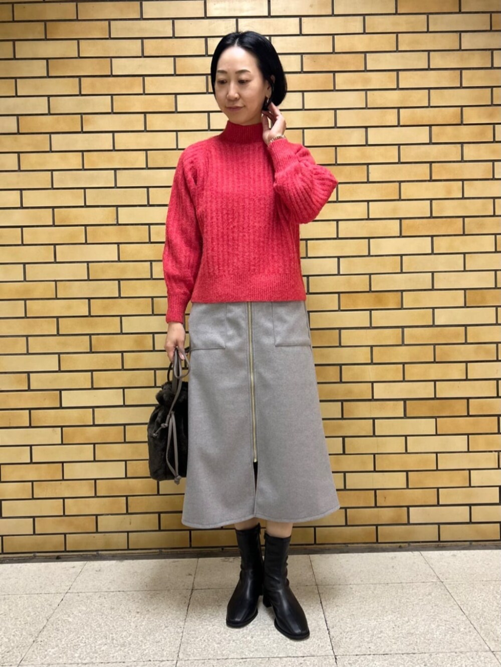 ブラック系のブーツ、ベージュ系のその他アウター、レッド系のニット/セーターを着用したレディースの冬コーディネートの4枚目の写真