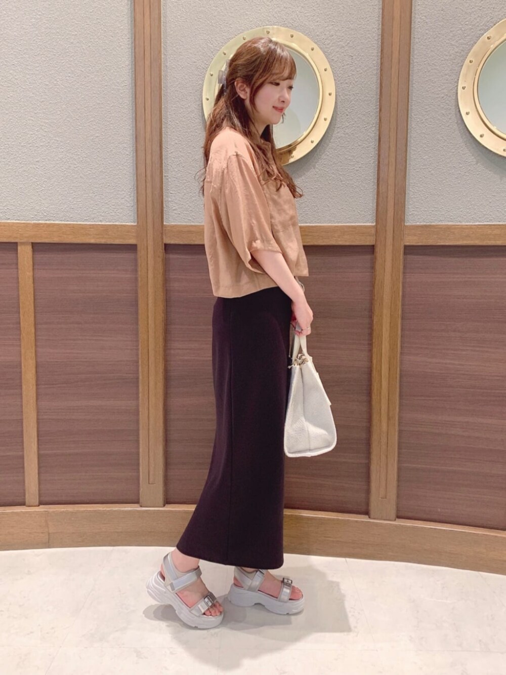 ベージュ系のハンドバッグ、イエロー系のシャツ/ブラウス、シルバー系のサンダルを着用したレディースの春コーディネートの2枚目の写真