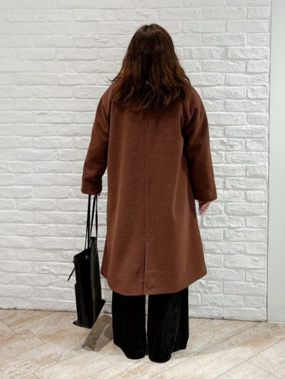 ブラウン系のステンカラーコート、ブラック系のその他パンツ、ブラック系のトートバッグを着用したレディースの冬コーディネートの3枚目の写真