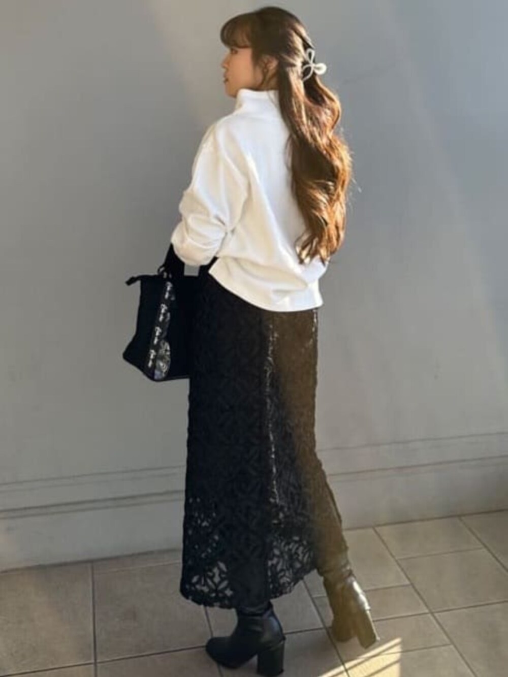 ブラック系のスカート、ホワイト系のTシャツ/カットソー、ブラック系のハンドバッグを着用したレディースの春コーディネートの4枚目の写真