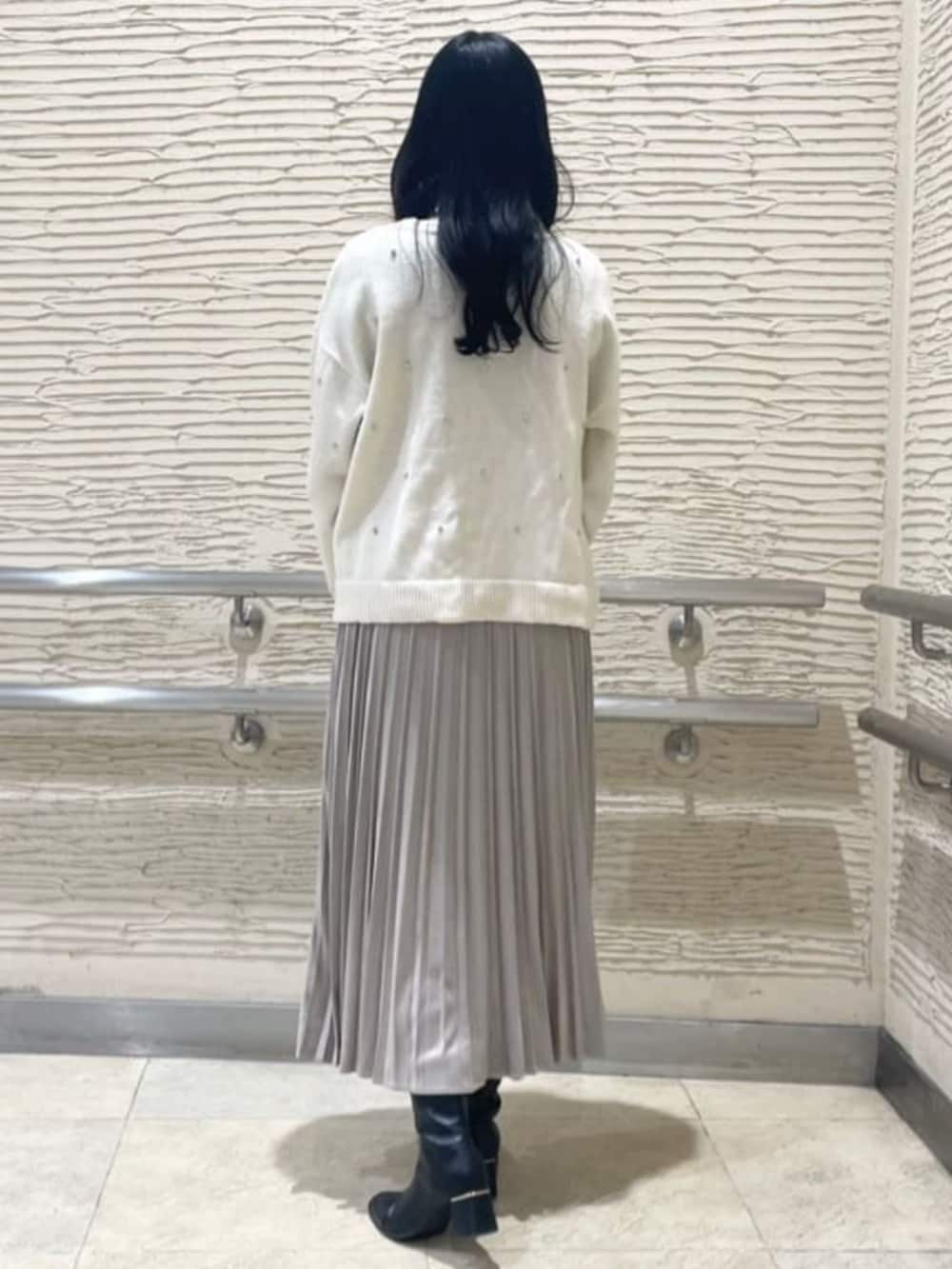 ブラック系のブーツ、ホワイト系のニット/セーター、ベージュ系のスカートを着用したレディースの冬コーディネートの3枚目の写真