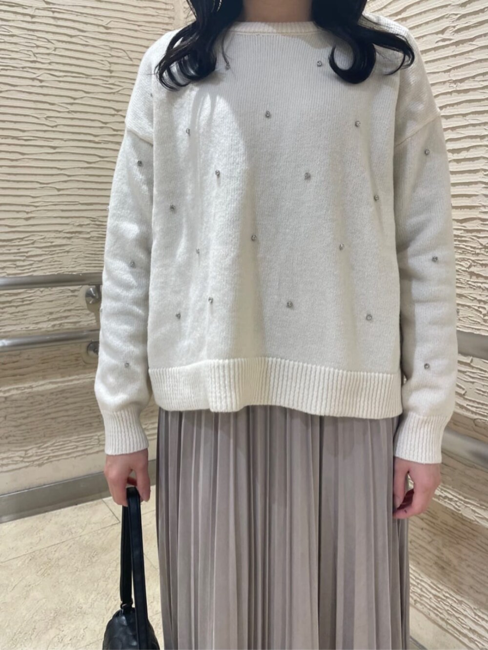 ブラック系のブーツ、ホワイト系のニット/セーター、ベージュ系のスカートを着用したレディースの冬コーディネートの4枚目の写真