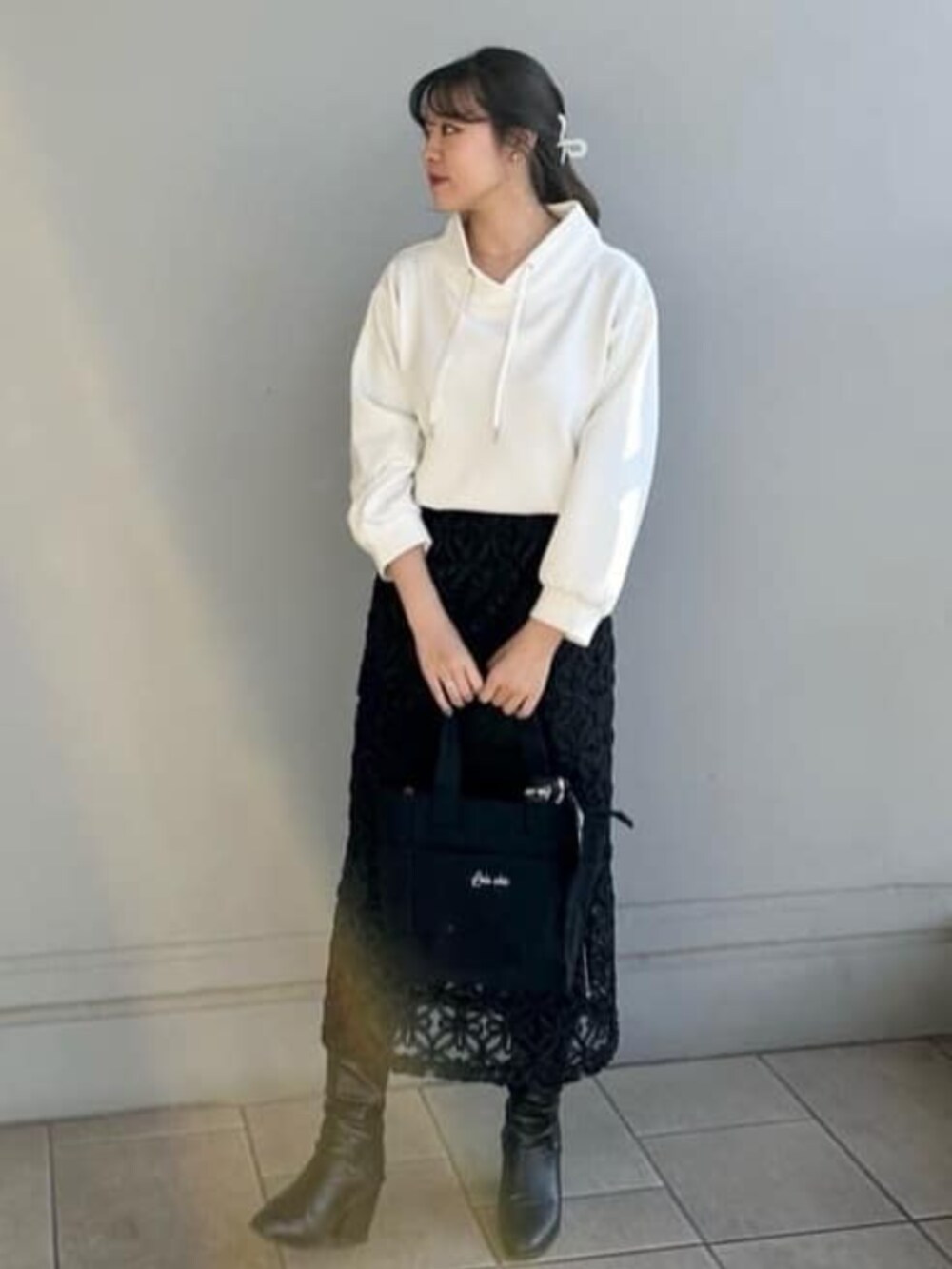 ブラック系のスカート、ホワイト系のTシャツ/カットソー、ブラック系のハンドバッグを着用したレディースの春コーディネートの2枚目の写真