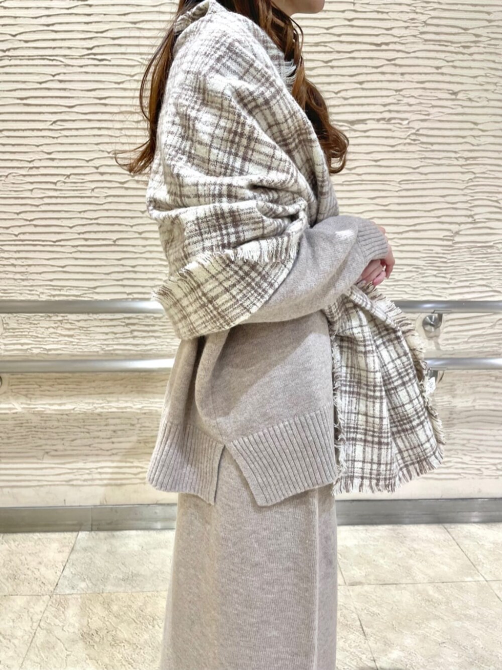 ブラック系のブーツ、ベージュ系のセットアップ、ベージュ系のストール/ショールを着用したレディースの冬コーディネートの5枚目の写真