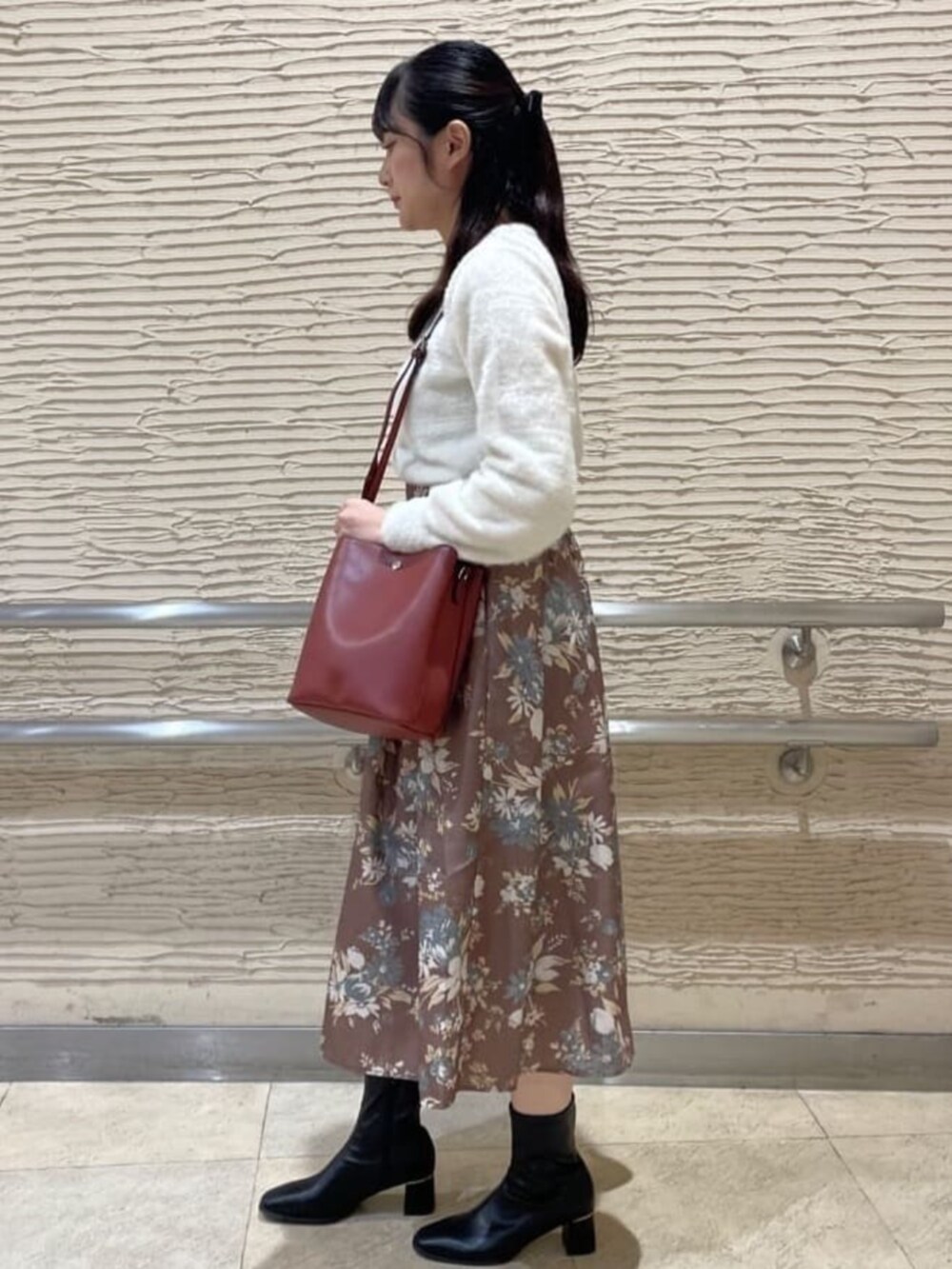 ブラック系のブーツ、ホワイト系のカーディガン/ボレロ、ブラウン系のスカートを着用したレディースの秋コーディネートの2枚目の写真