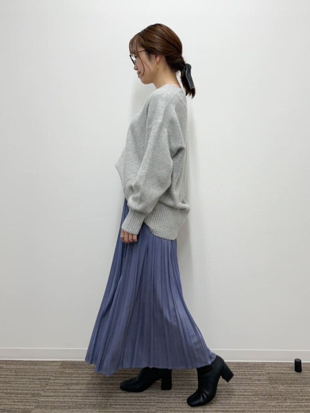グレー系のニット/セーター、ブルー系のスカート、ブラック系のブーツを着用したレディースの秋コーディネートの2枚目の写真