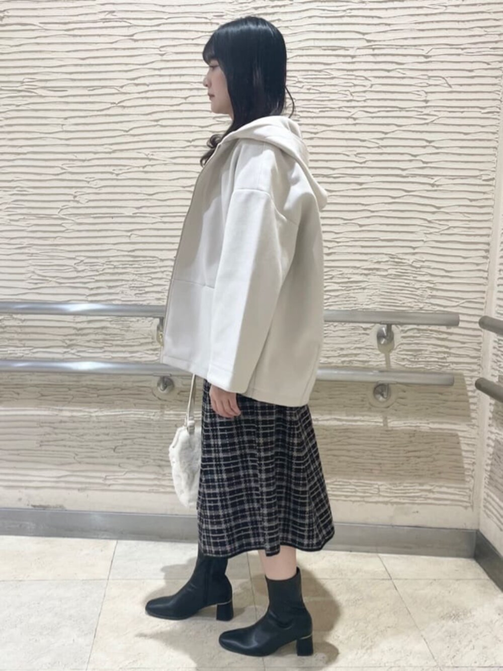 ブラック系のブーツ、ホワイト系のその他アウター、ベージュ系のワンピースを着用したレディースの冬コーディネートの2枚目の写真