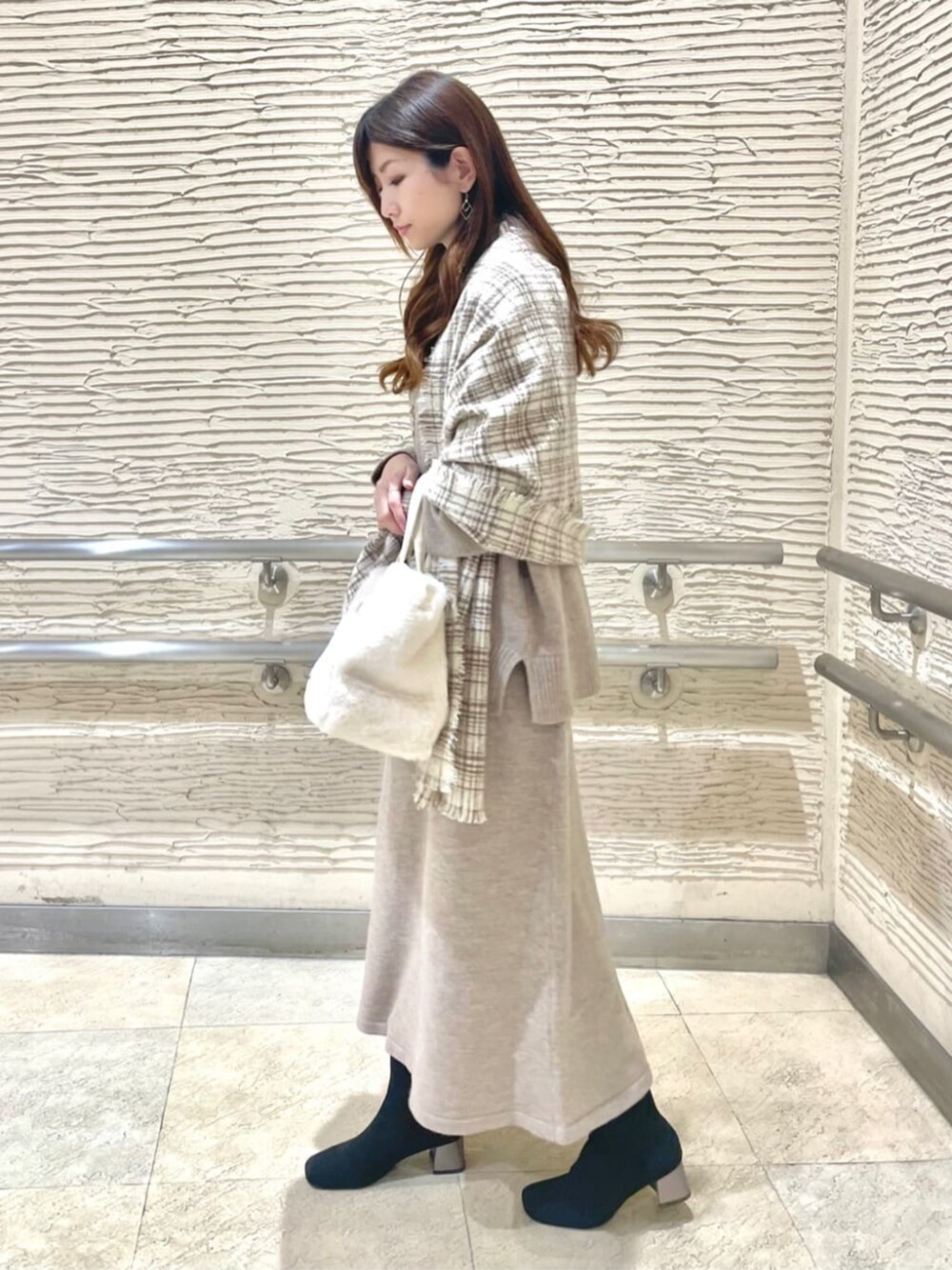 ブラック系のブーツ、ベージュ系のセットアップ、ベージュ系のストール/ショールを着用したレディースの冬コーディネートの2枚目の写真