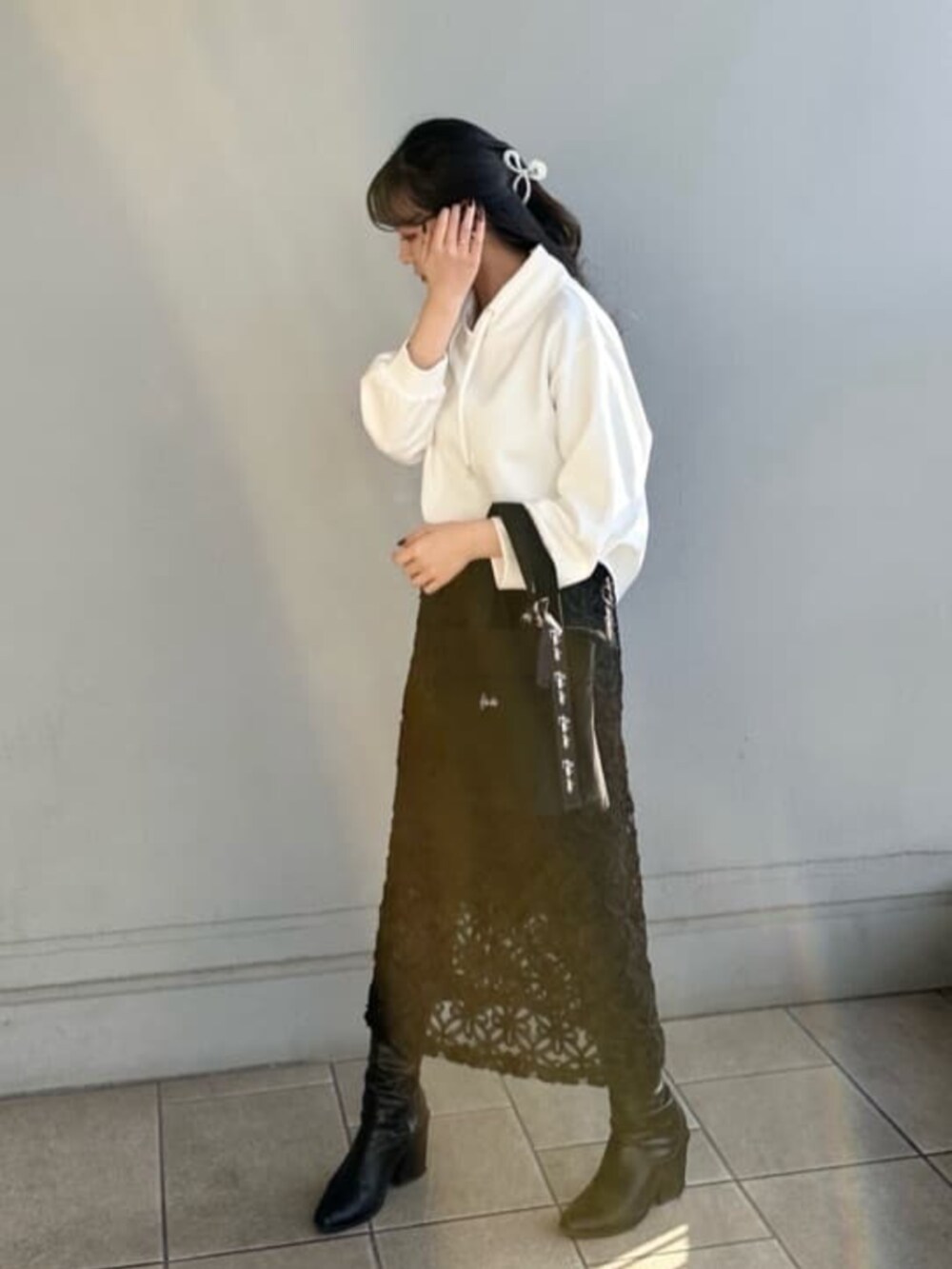 ブラック系のスカート、ホワイト系のTシャツ/カットソー、ブラック系のハンドバッグを着用したレディースの春コーディネートの3枚目の写真