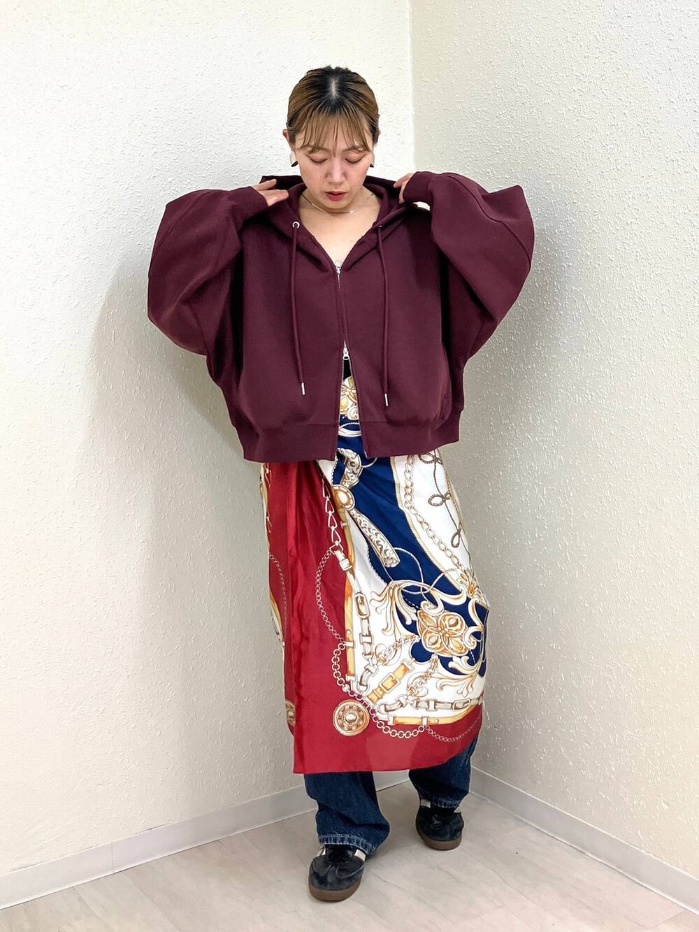 ブルー系のデニムパンツ、レッド系のパーカー、その他のネックレスを着用したレディースの秋コーディネートの4枚目の写真