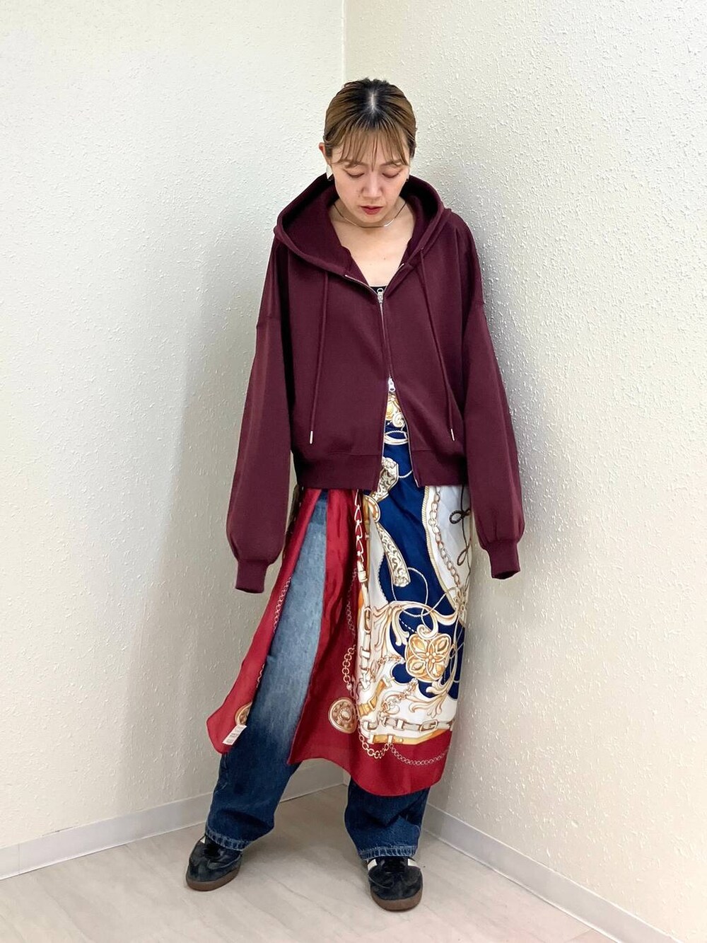 ブルー系のデニムパンツ、レッド系のパーカー、その他のネックレスを着用したレディースの秋コーディネートの2枚目の写真