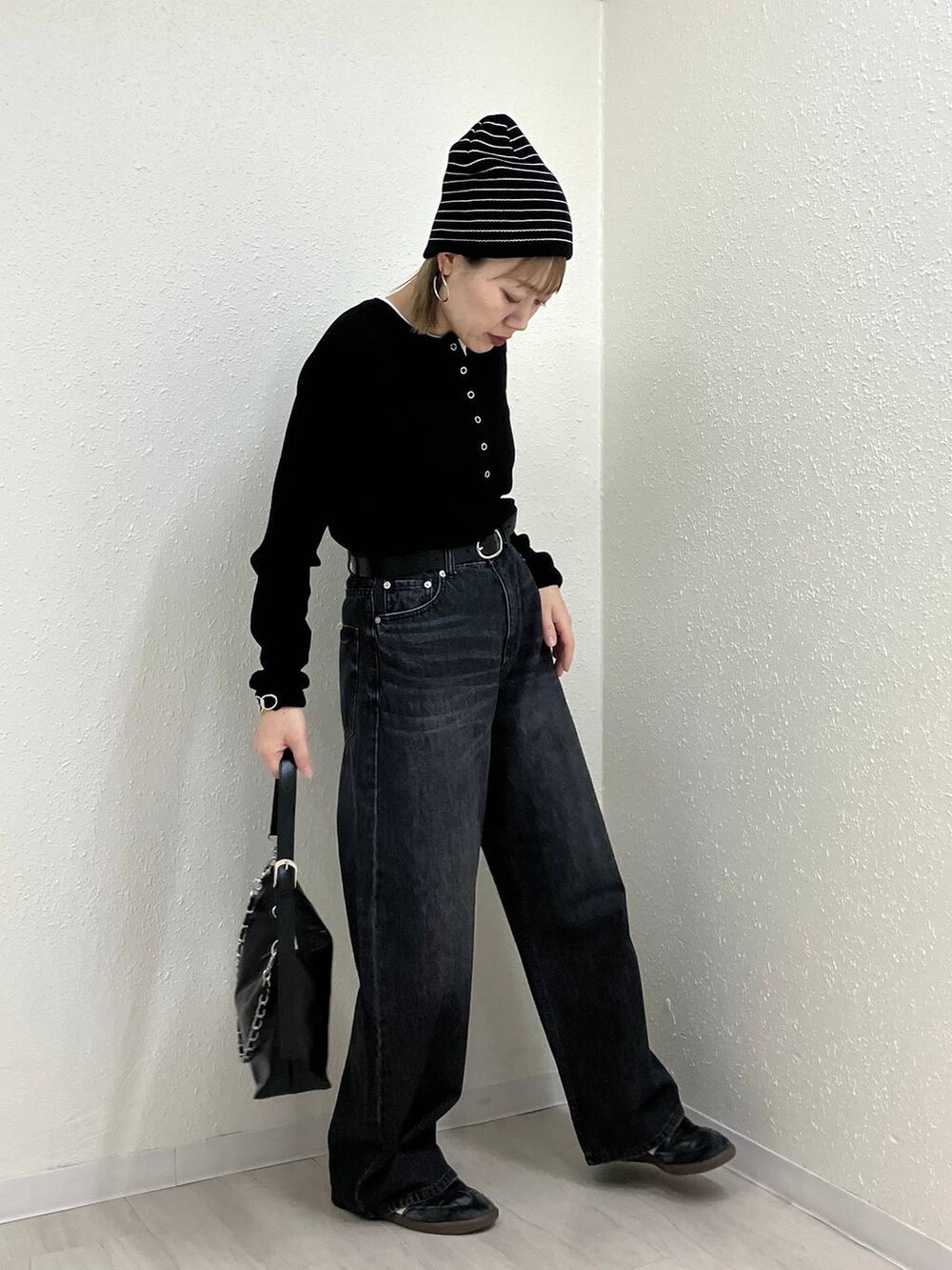 ブラック系のニット/セーター、ブラック系のデニムパンツ、ブラック系のショルダーバッグを着用したレディースの冬コーディネートの3枚目の写真