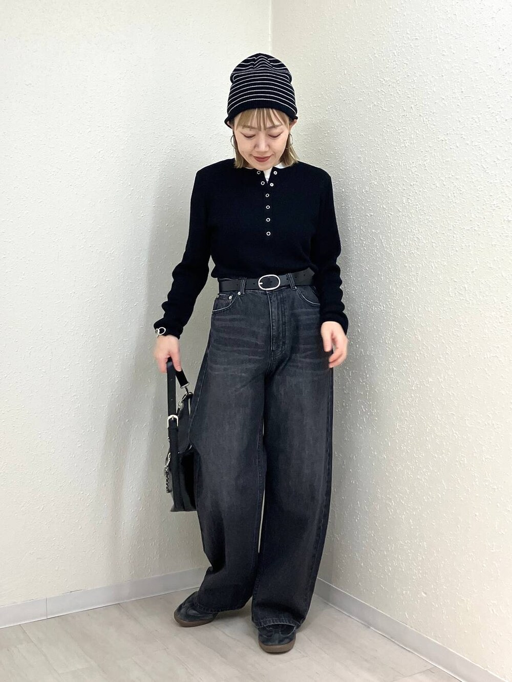 ブラック系のニット/セーター、ブラック系のデニムパンツ、ブラック系のショルダーバッグを着用したレディースの冬コーディネートの2枚目の写真