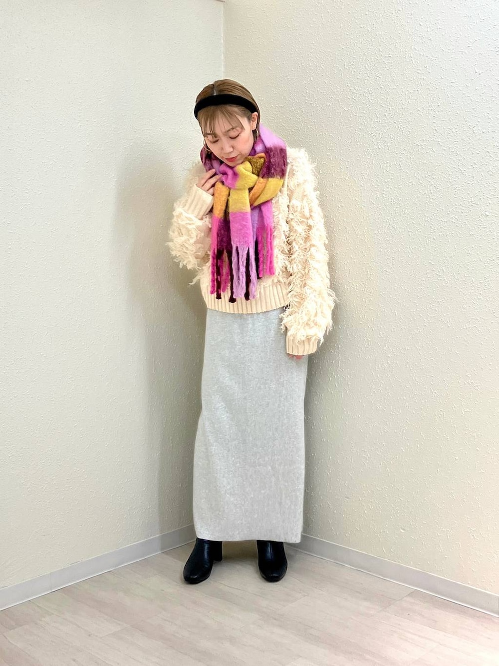 グレー系のスカート、ブラック系のブーツ、ホワイト系のカーディガン/ボレロを着用したレディースの冬コーディネートの4枚目の写真