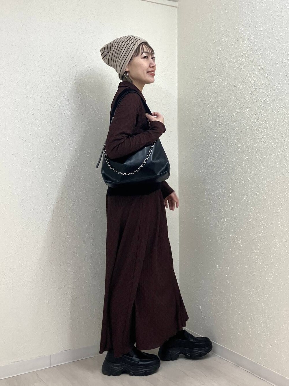 ブラック系のショルダーバッグ、ブラック系のローファー、ブラウン系のワンピースを着用したレディースの冬コーディネートの4枚目の写真