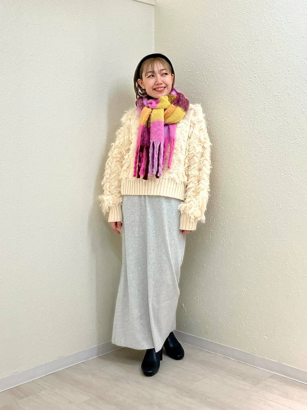 グレー系のスカート、ブラック系のブーツ、ホワイト系のカーディガン/ボレロを着用したレディースの冬コーディネートの3枚目の写真