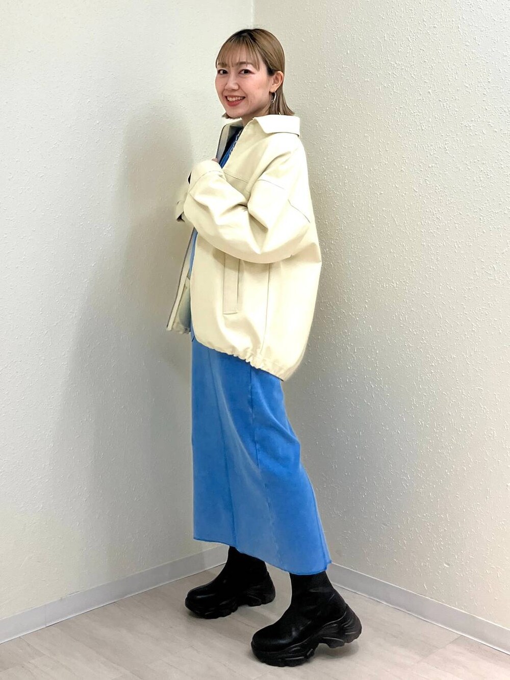 ブラック系のブーツ、ホワイト系のブルゾン、ブルー系のワンピースを着用したレディースの冬コーディネートの3枚目の写真