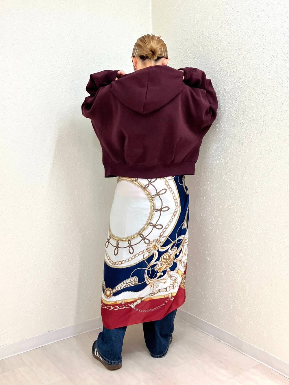 ブルー系のデニムパンツ、レッド系のパーカー、その他のネックレスを着用したレディースの秋コーディネートの3枚目の写真