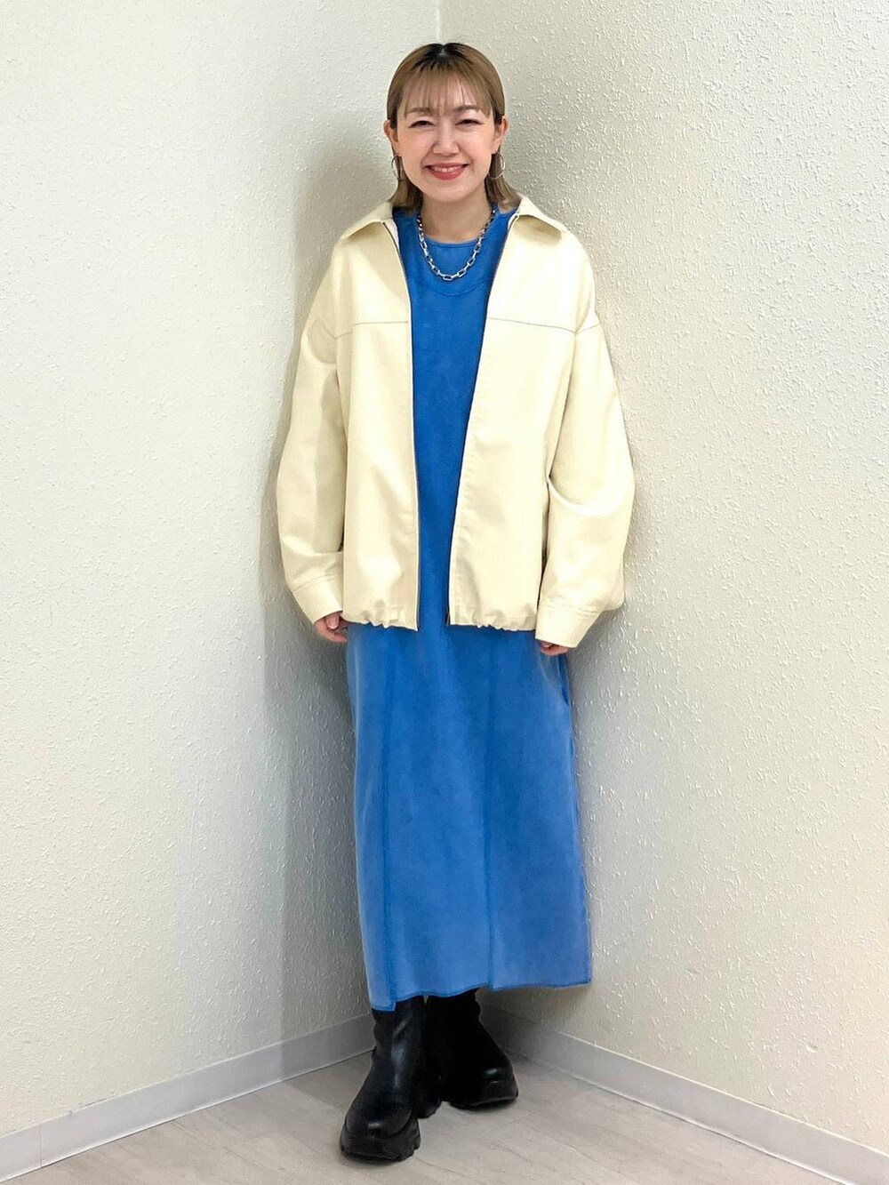 ブラック系のブーツ、ホワイト系のブルゾン、ブルー系のワンピースを着用したレディースの冬コーディネートの2枚目の写真