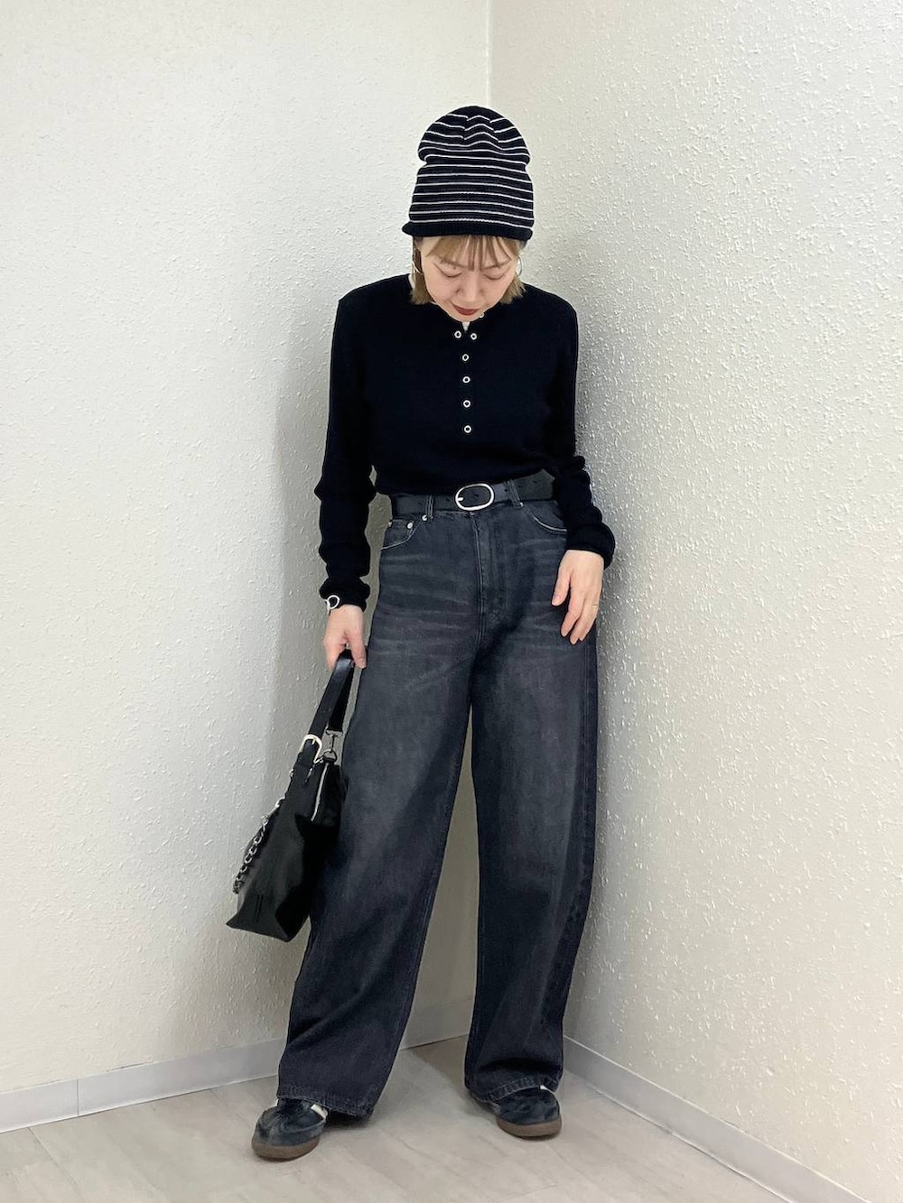 ブラック系のニット/セーター、ブラック系のデニムパンツ、ブラック系のショルダーバッグを着用したレディースの冬コーディネートの8枚目の写真