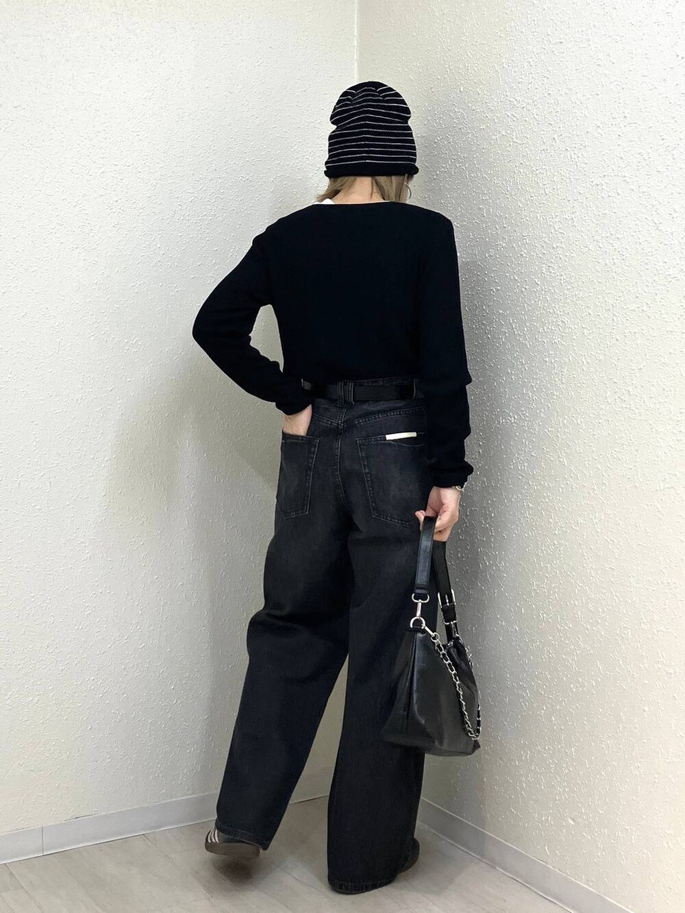 ブラック系のニット/セーター、ブラック系のデニムパンツ、ブラック系のショルダーバッグを着用したレディースの冬コーディネートの4枚目の写真