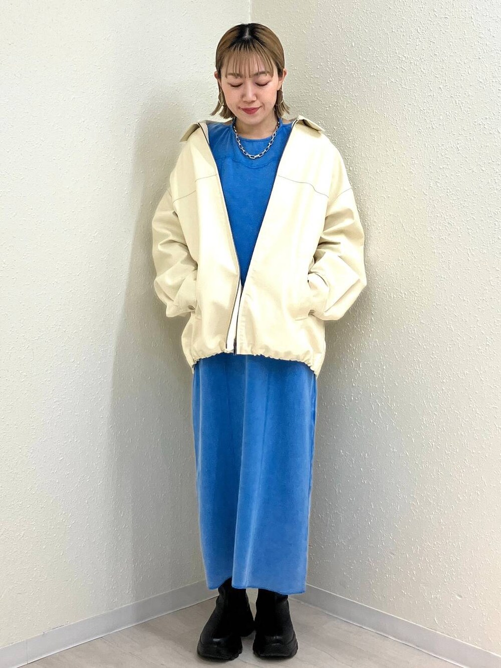 ブラック系のブーツ、ホワイト系のブルゾン、ブルー系のワンピースを着用したレディースの冬コーディネートの6枚目の写真