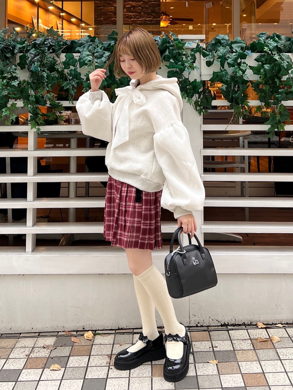 ブラック系のローファー、ホワイト系のパーカー、ブラック系のボストンバッグを着用したレディースの冬コーディネートの3枚目の写真