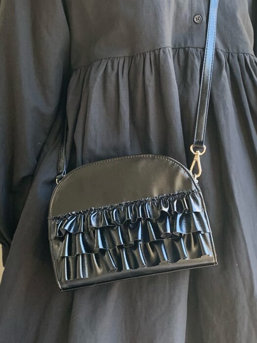 ブラック系のパンプス、ブラック系のワンピース、ブラック系のショルダーバッグを着用したレディースの冬コーディネートの7枚目の写真